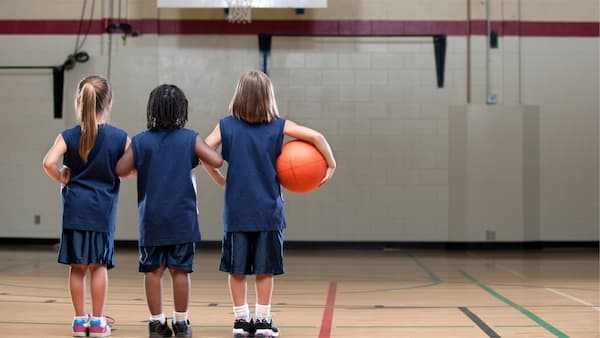 Tres niños de espaldas en una cancha de baloncesto
